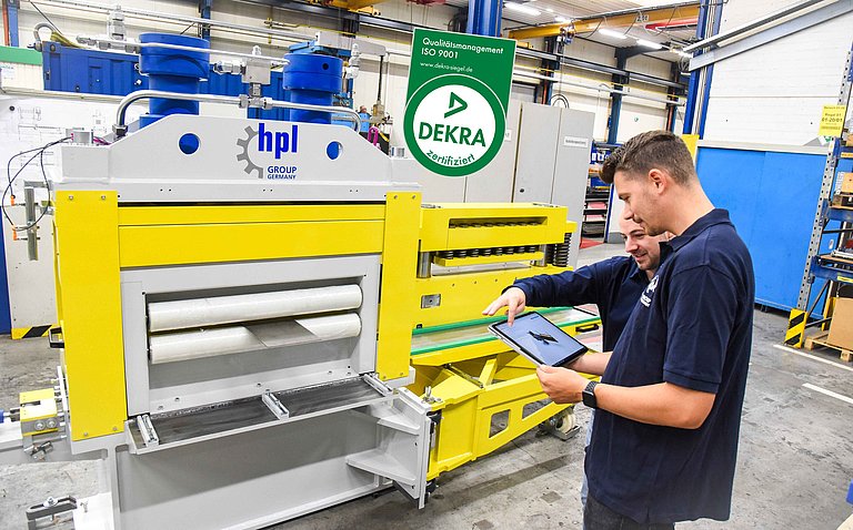 Zwei Mitarbeitende besprechen den digitalen Entwurf einer Sondermaschine vor einer hpl-Anlage